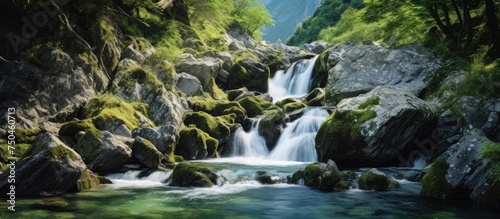 Serene miniature waterfall cascading in a rocky alpine stream under mountain backdrop