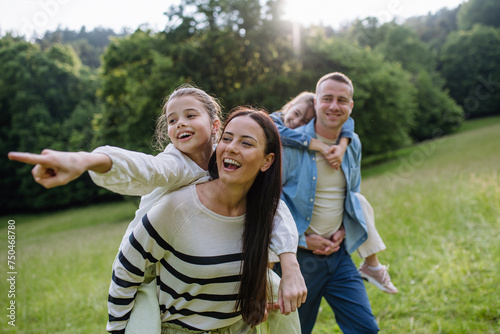 Portrait of beautiful family, parents piggibacking two daughters, having fun in nature. photo