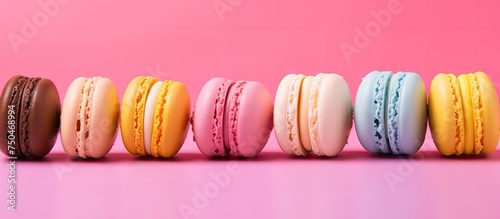 Vibrant Macarons Arranged in a Colorful Line on a Soft Pink Background