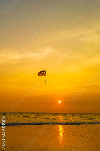 Parasailing extreme sports on beach in sunset background. Paragliding in front of an amazing sunset. A beautiful background of a parasailing parachute on the backdrop a sunset on an evening sky.