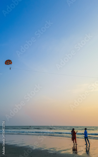 Parasailing extreme sports on beach in blue sky background. Man is parasailing in the blue sky. Paragliding in the clear sky above the sea.