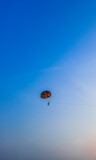 Parasailing extreme sports on beach in blue sky background. Man is parasailing in the blue sky. Paragliding in the clear sky above the sea.