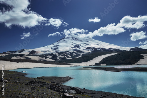 Caucasus Elbrus majestic mountain peak, blue sky lake, snow covered glacier, rocky landscape, alpine scenery