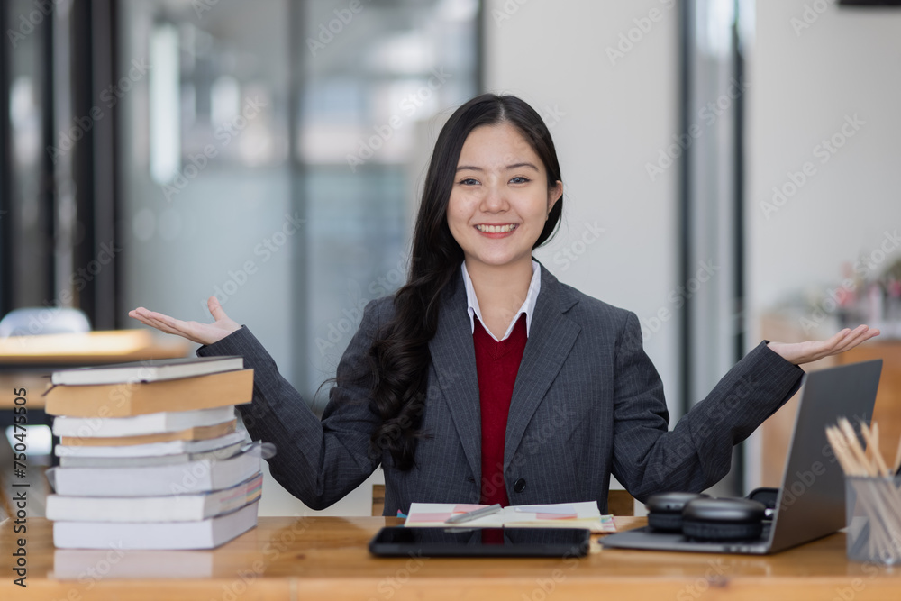 Happy young asian woman wearing earphones and using laptop computer at desk in office, Female student with stack of books and laptop. Happy young asian woman wearing earphones and using laptop computer at desk in office, Female student with stack of books and laptop.