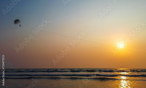 Parasailing extreme sports on beach in sunset background. Paragliding in front of an amazing sunset. A beautiful background of a parasailing parachute on the backdrop a sunset on an evening sky.