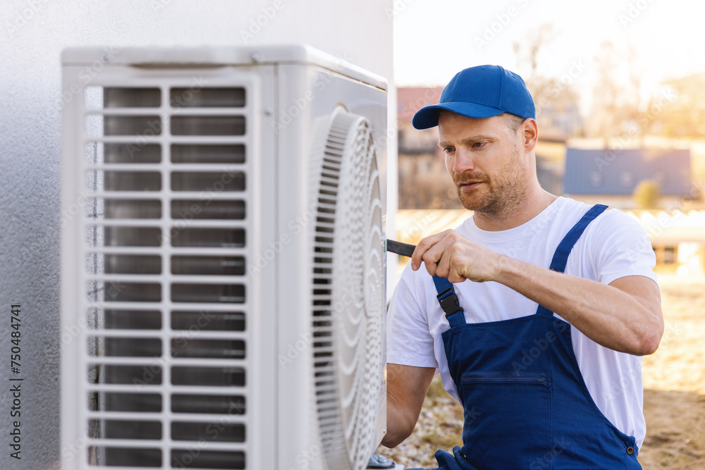 technician working on air conditioning or heat pump outdoor unit. HVAC service, maintenance and repair - obrazy, fototapety, plakaty 