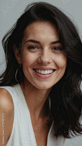 A beautiful young caucasian girl with dark hair smiles happily.