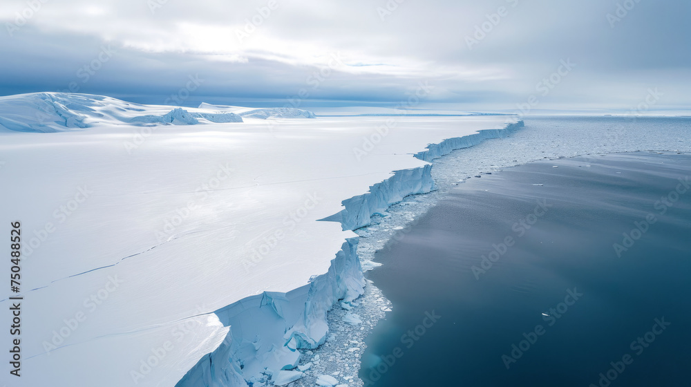 Ice floe landscape wide view with a very quiet blue ocean with a large ice pieces zone along the coast and a cloudy sky