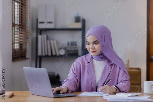 Φωτογραφία Asian islamic woman using laptop computer at desk in office.