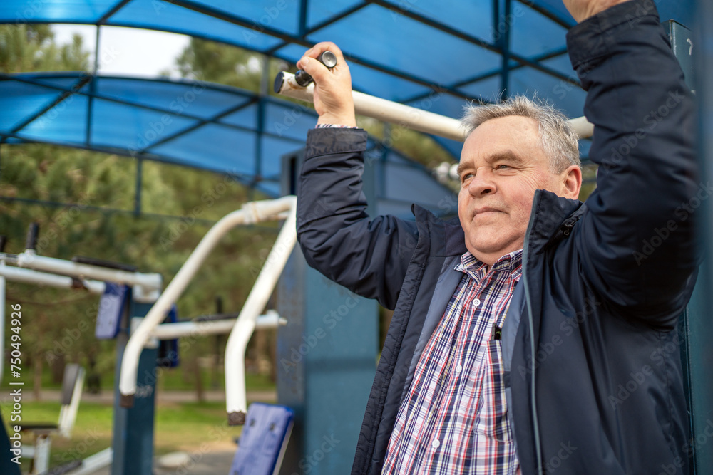 Mature man with content expression working out on exercise equipment in outdoor park setting. Mature man with content expression working out on exercise equipment in outdoor park setting.