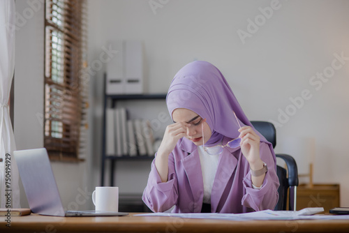 Young asian islamic women stressed from work at office desk.