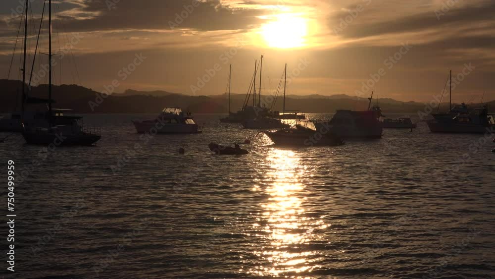 Recreational vessels, both power boats and yachts on moorings near Russell wharf at sunset. Location: Russell, New Zealand Recreational vessels, both power boats and yachts on moorings near Russell wharf at sunset. Location: Russell, New Zealand