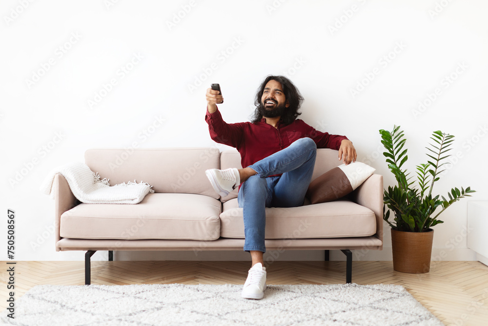 Relaxed young indian man watching TV at home
