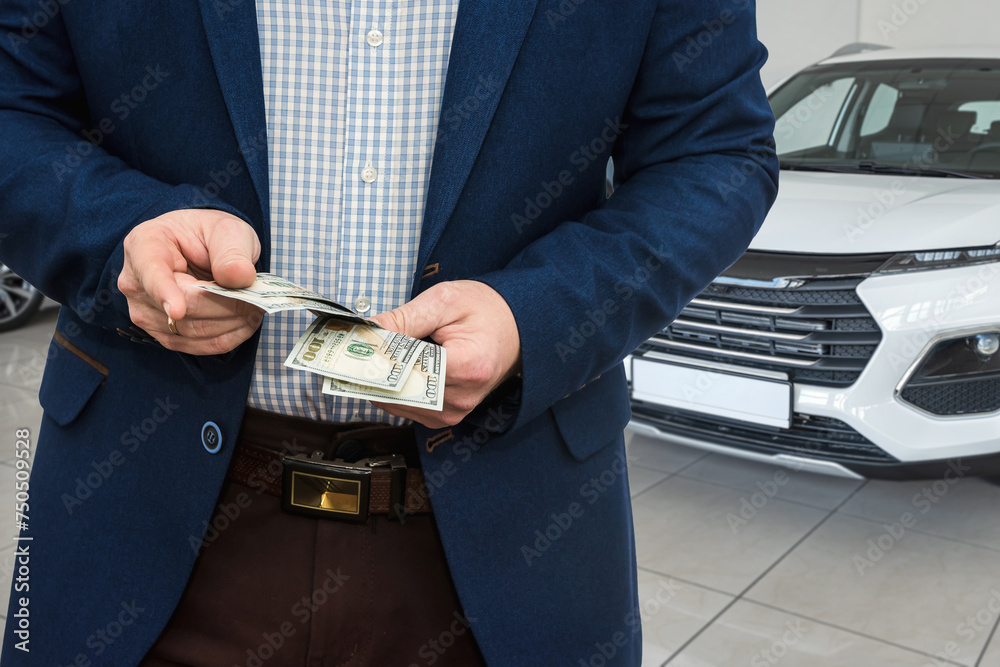 Φωτογραφία Businessman holding dollar money in car showroom, deal of buying or renting car
