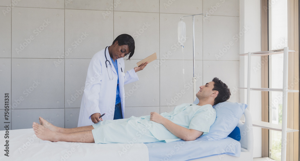Obraz premium Portrait patient caucasian man lying bed with woman doctor African-American standing carer physical therapist two people talk helping support and check treat sick person inside hospital room service.