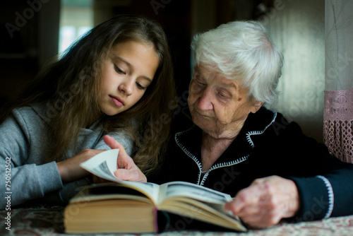 A grandmother reads a book with her preschool granddaughter.