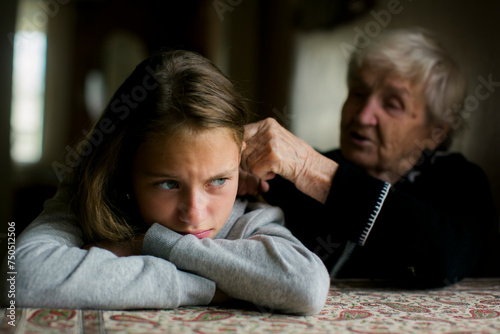 A grandmother brushes her disgruntled granddaughter's hair.