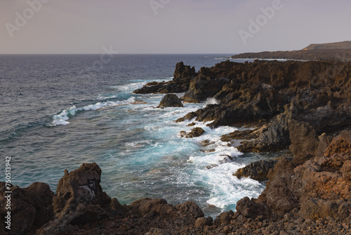 Los Hervideros,rugged volcanic coastline known for waves crashing into sea caves & picturesque views.