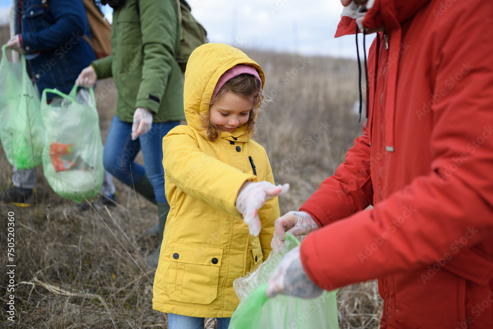 Little girl among eco activists picking up litter in nature, environmental pollution, eco activism and plogging concept. Little girl among eco activists picking up litter in nature, environmental pollution, eco activism and plogging concept.