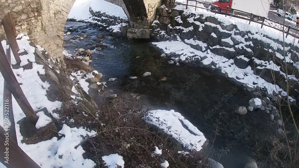 rio helado con puente antiguo en la montaña