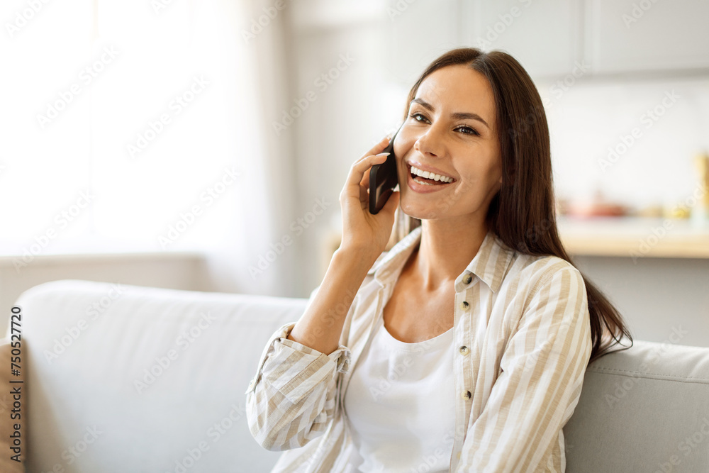 Delighted young woman enjoying pleasant conversation on her mobile phone at home Delighted young woman enjoying pleasant conversation on her mobile phone at home