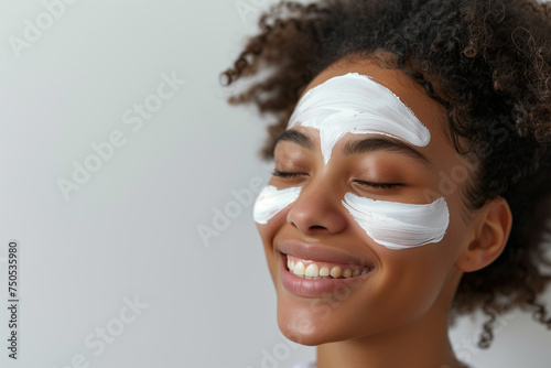 Woman applying facial clay mask. Beautiful girl with cosmetic peel off mask on her face. Beauty and spa treatment. Natural skin care and cleansing concept photo