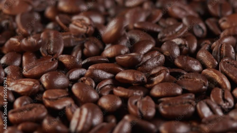Roasted coffee beans dolly shot. Aromatic coffee beans move slowly. Slide slow motion close-up of whole roasted coffee beans.