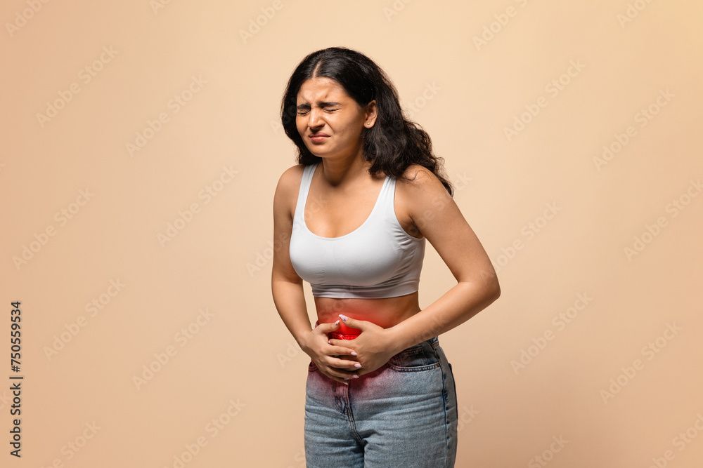 Sick indian woman having stomach ache, touching abdomen with red inflamed zone Sick indian woman having stomach ache, touching abdomen with red inflamed zone