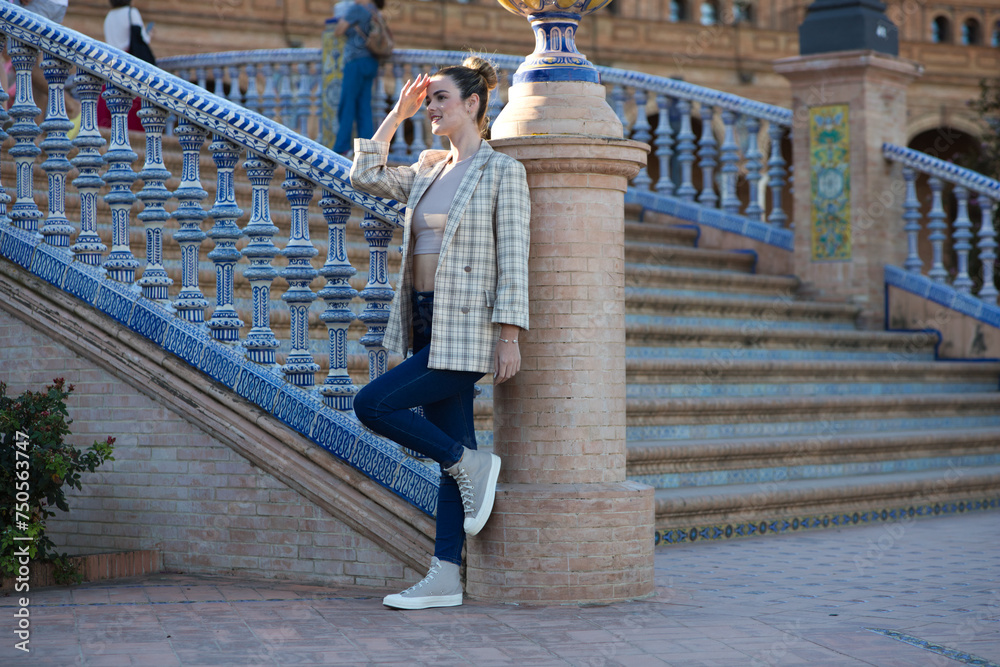 Young and beautiful woman in casual clothes is visiting the famous Plaza de Espana in Seville. The woman enjoys travelling around the old european city. Holiday and travel concept.