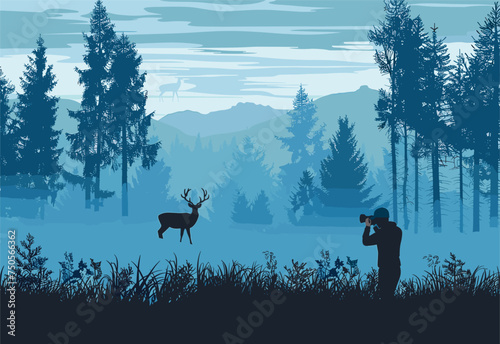A man capturing a photo of a deer in the natural landscape of the woods with snowcapped mountains in the background, creating a picturesque scene