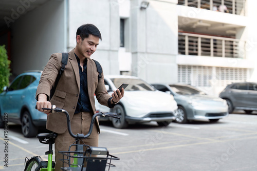 Asian businessman in a suit is riding a bicycle on the city streets for his morning commute to work. Eco transportation concept, sustainable lifestyle concept