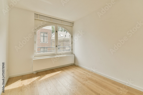Bright empty room with large arched window and wooden floor photo
