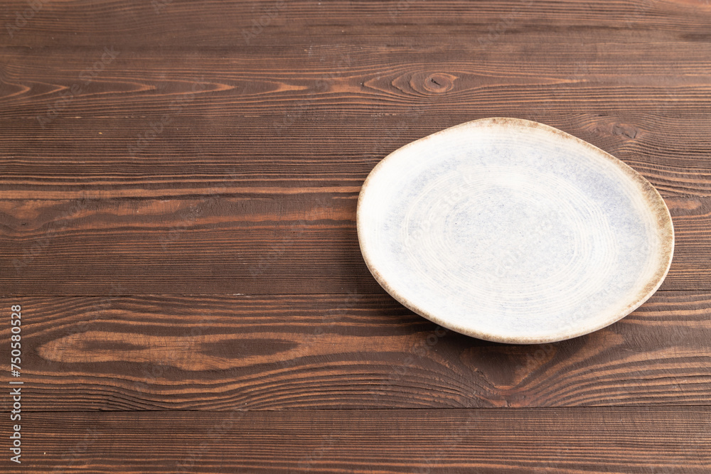 Empty blue and white ceramic plate on brown wooden. Side view, copy space Empty blue and white ceramic plate on brown wooden. Side view, copy space