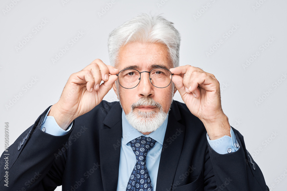 Confident senior businessman adjusting glasses, isolated on grey background. Confident senior businessman adjusting glasses, isolated on grey background.