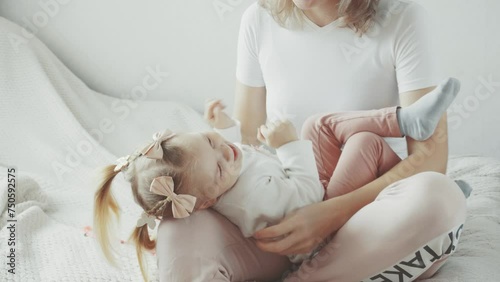 Mom plays tickle with her little daughter. light video photo