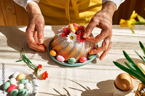 Photography Female hands decorating Easter cake with small colorful chocolate eggs and daisy flowers