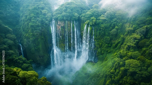 Breathtaking Aerial View of Majestic Waterfall in Lush Green Tropical Forest with Mist and Sunrays