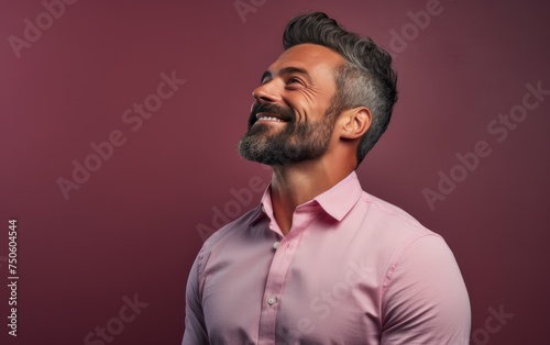 A man with a beard and a pink shirt is smiling