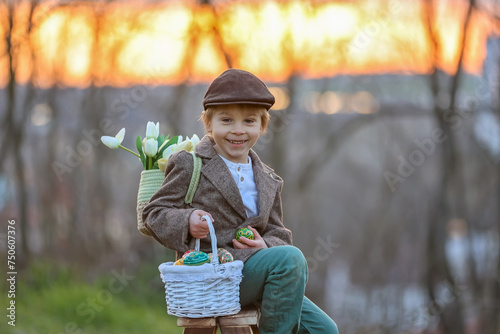 Beautiful stylish toddler child, boy, playing with Easter decoration in the park, springtime
