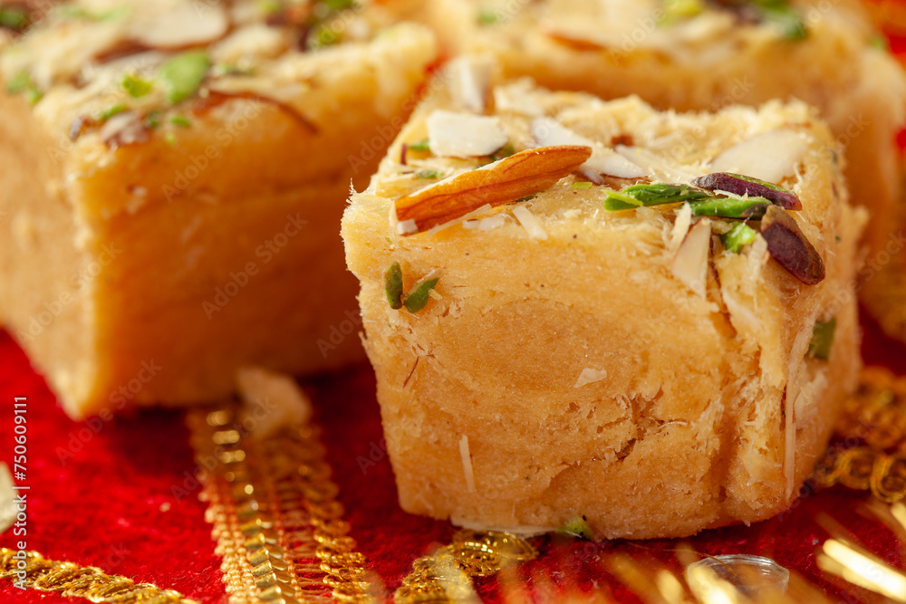 Traditional Indian sweets on a decorative red fabric with golden embroidery Traditional Indian sweets on a decorative red fabric with golden embroidery