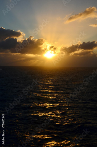 Golden sunset at sea  reflections on water surface  cloudy sky with sunset light sunrays