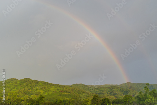 Rural landscape mountain hill with Rainbow over stormy sky.