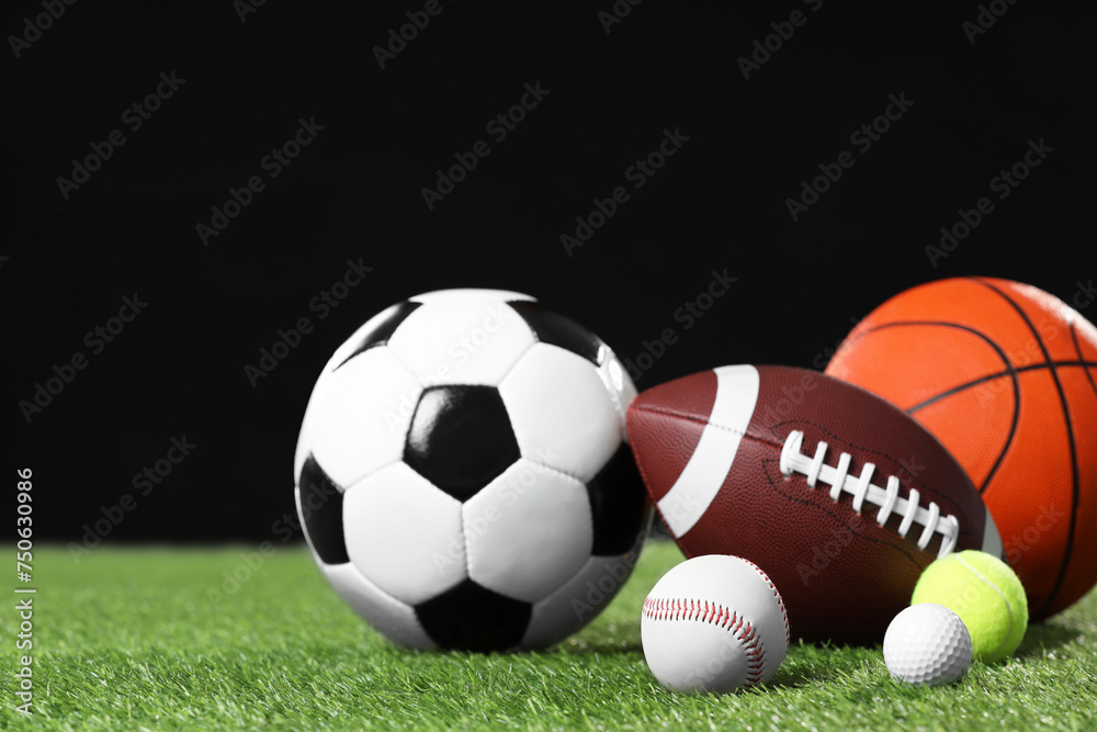Many different sports balls on green grass against black background, space for text Many different sports balls on green grass against black background, space for text