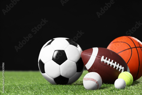 Many different sports balls on green grass against black background  space for text