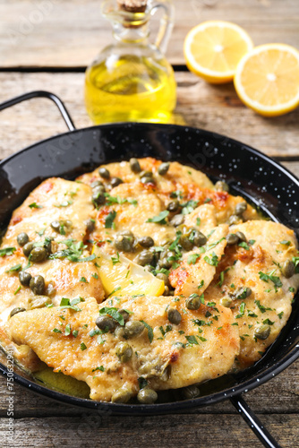 Delicious chicken piccata with herbs on wooden table
