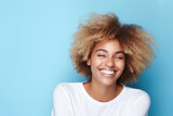 A beautiful African American woman with a short haircut joyfully laughs on a blue background.	
