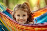 Cute little smiling girl relaxing on a colorful hammock