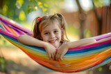 Cute little smiling girl relaxing on a colorful hammock