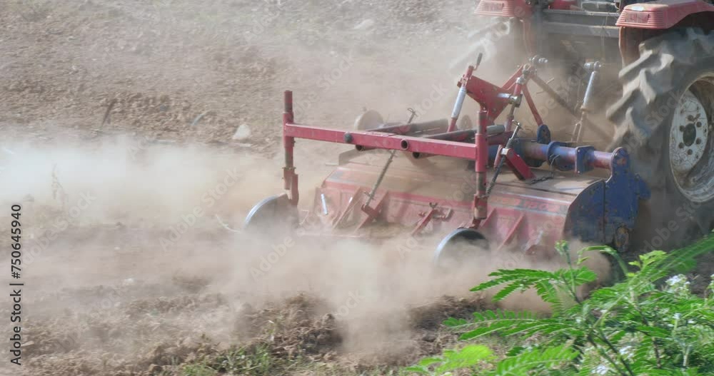 close up of the tractor plowing a field. The tractor is pulling a plow ...