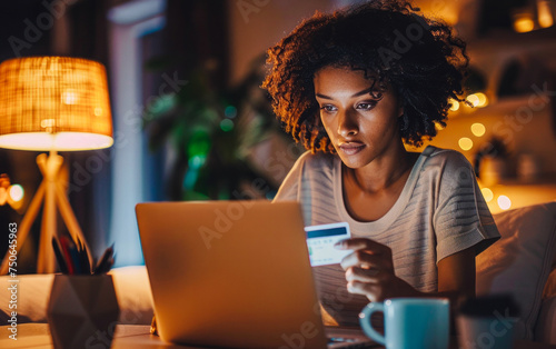 Young woman uses laptop and credit card at home office, symbolizing digital economy's efficiency and accessibility.